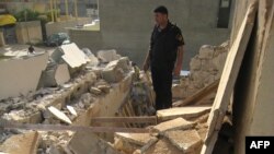 شرطي يتفحص آثار تفجير منزل الصالحي بكركوك