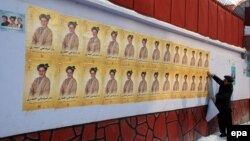 A boy pastes election campaign posters onto a wall in Mazar-e Sharif. (file photo)