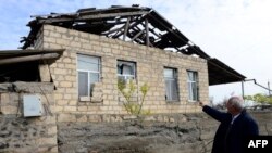 Azerbaijan -- An Azeri man points at a house damaged during clashes between Armenian and Azeri forces in the settlement of Gapanli, outside the frontline Azeri town of Terter, April 5, 2016