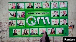 Iraq -- A woman walks past a Patriotic Union of Kurdistan (PUK) campaign poster for Iraq's parliamentary elections in Sulaimaniya, April 28, 2014
