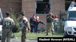 Security forces stand guard outside a school in Beslan while emergency crews work inside in 2004 photo.