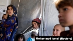 FILE: Internally displaced Afghan children arrive to study inside a tent at a refugee camp in the western province of Herat.