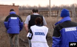 International OSCE monitors walk toward a hangar to witness the removal of heavy weapons by officials of the self-proclaimed "People's Republic of Donetsk" in Snizhne on March 7.