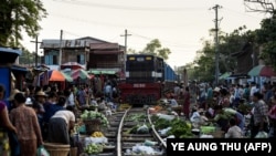 Поезд медленно проезжает мимо продавцов в Мандалае, 19 мая 2019 года.