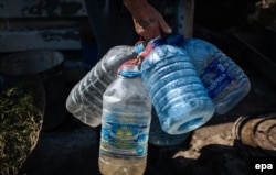 Житель Авдіївки прийшов набрати воду у великі пластикові пляшки (архівне фото)