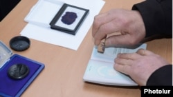 Armenia - An official at a polling station in Yerevan puts a special stamp on a voter's passport which is supposed to prevent multiple voting, 18Feb2013.
