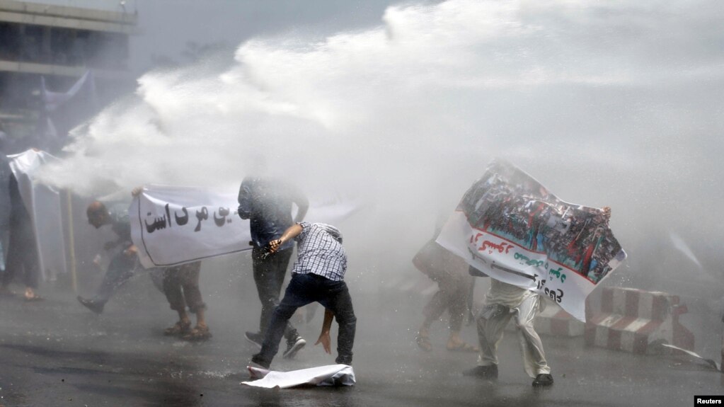Afghan protesters are hit by a water cannon during a protest in Kabul on June 2.