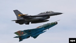 Un avion american F16 și unul MIG 21 Lancer, aparținînd forțelor aviatice române, efectuînd o manevră de apropiere în cursul exercițiilor militare comune „Vipera dacă 2014”, la baza aeriană de la Cîmpia Turzii 