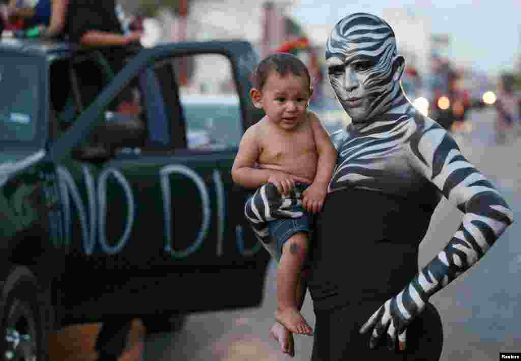 A reveller holds a child while posing for a picture during a gay-pride parade in Ciudad Juarez, Mexico. (Reuters/Jose Luis Gonzalez)