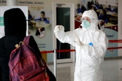 Një punonjës mjekësor kontrollon një pasagjere shqiptare që ka arritur në Shqipëri përmes Aeroportit të Tiranës.