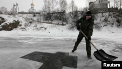 A worker prepares a cross-shaped bathing hole for Russian Orthodox Epiphany celebrations on the Mana River near the village of Ust-Mana on January 18.