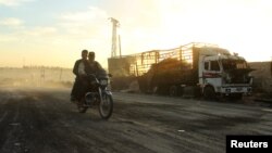Чоловіки на мотоциклі минають знищену авіаударом вантажівку поблизу Алеппо, 20 вересня 2016 року