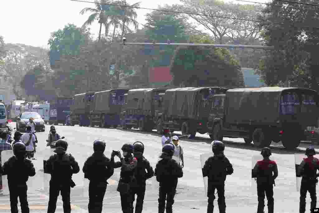 A row of riot police block a road behind military trucks full of riot police near the U.S. Embassy in Yangon, Myanmar Monday, Feb. 22, 2021.