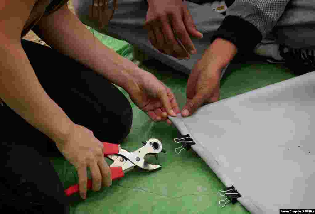 First, a volunteer demonstrates how to bind the material using a rivet gun. It was the first time using such a tool for many young migrants.