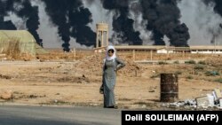 د شام له راس العین ښار سره یوه ښځه ولاړ ده. په اکتوبر کې ترکیو الوتکو په سیمه بمباري وکړه. (ارشیف)