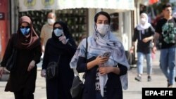 Иранцы в масках идут по улице Тегерана. 4 августа 2020 года.
