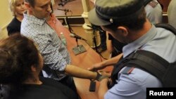 A policeman puts handcuffs on opposition leader Aleksei Navalny (left) in a courtroom in Kirov on July 18. The next day, Navalny was freed as appeals of his five-year sentence are heard.