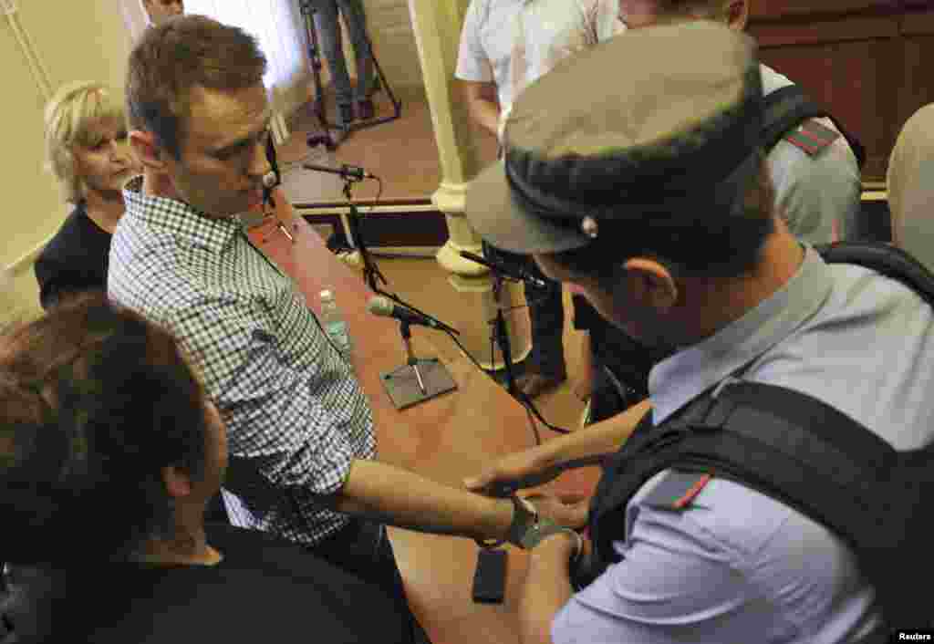 A policeman puts handcuffs on protest leader Aleksei Navalny inside the courtroom in Kirov.