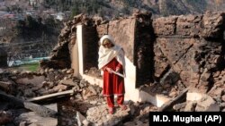 A Kashmiri woman stands amid the debris of her home that was reportedly destroyed by cross-border shelling from Indian troops, in the Neelum Valley, situated at the de facto border in Pakistani Kashmir on December 23. 