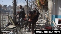 Afghan volunteers carry a victim at the scene of a car bomb that exploded in front of the old Ministry of Interior building in Kabul on January 27.