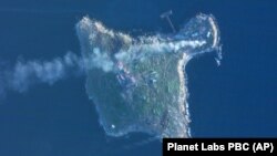 На супутниковому знімку, зробленому Planet Labs PBC, видно дим, який піднімається після ударів армії України по російських позиціях і гелікоптері на острові Зміїний у Чорному морі, 8 травня 2022 року