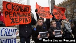People hold placards during a demonstration in Kemerovo on March 27. The signs say: "How many real victims?"; "Who is really to blame?"; "How much do your closed eyes cost?"; and "Corruption kills."