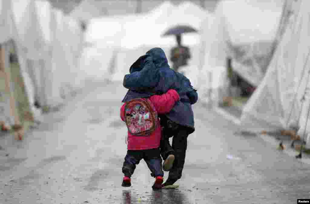 Syrian boys walk shoulder-to-shoulder in the rain at the Boynuyogun refugee camp on the Turkish-Syrian border.