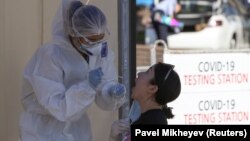 Медработник забирает мазок у пациента в пункте тестирования на коронавирус.