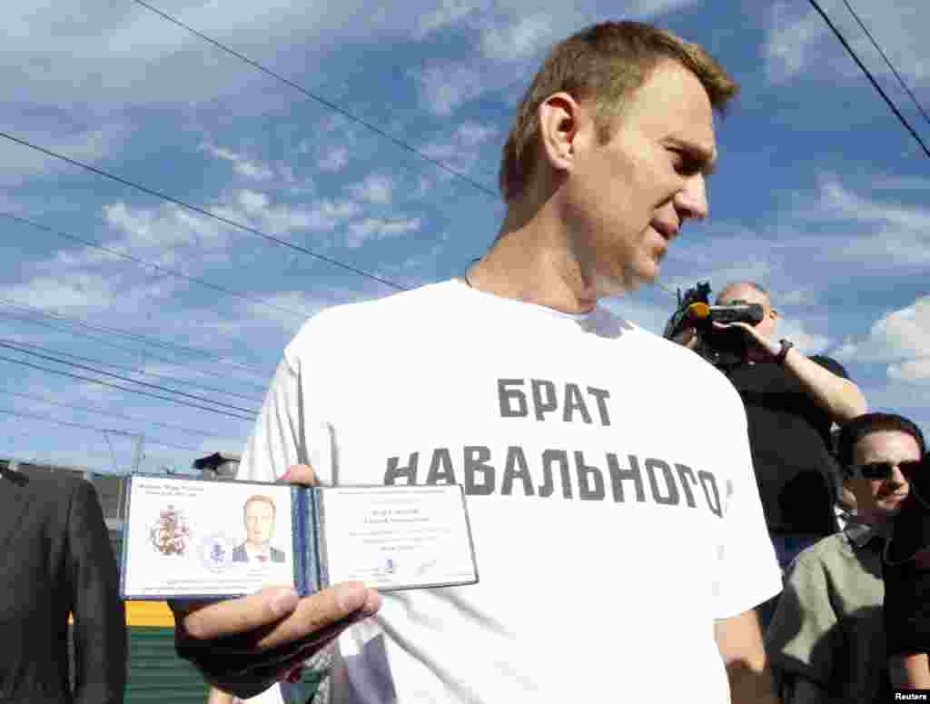 Russian anticorruption blogger Aleksei Navalny holds his Moscow mayoral candidate registration certificate before leaving boarding train from Moscow to Kirov where he is facing trial on embezzlement charges. (Reuters/Grigory Dukor)