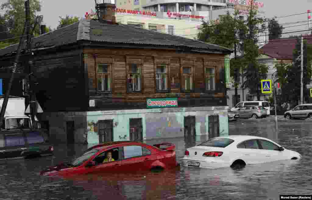 A woman uses her phone as she sits in her car on a flooded street in Nizhny Novgorod, Russia. (Reuters/Murad Sezer)