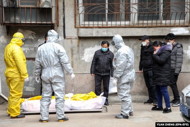 Родственники и работники похоронного дома в Ухане забирают тело человека, умершего от COVID-19, 1 февраля 2020 года