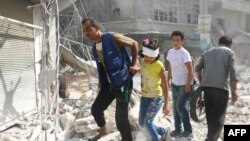 Syrians walk over rubble following air strikes on the rebel-held Fardus neighborhood of the embattled Syrian city of Aleppo on October 12.