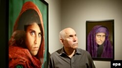 U.S. photographer Steve McCurry stands between the picture that made the 1985 cover of National Geographic and another of grown-up Sharbat Gula at an exhibition at the Museum of Arts and Crafts in Hamburg, Germany in 2013.