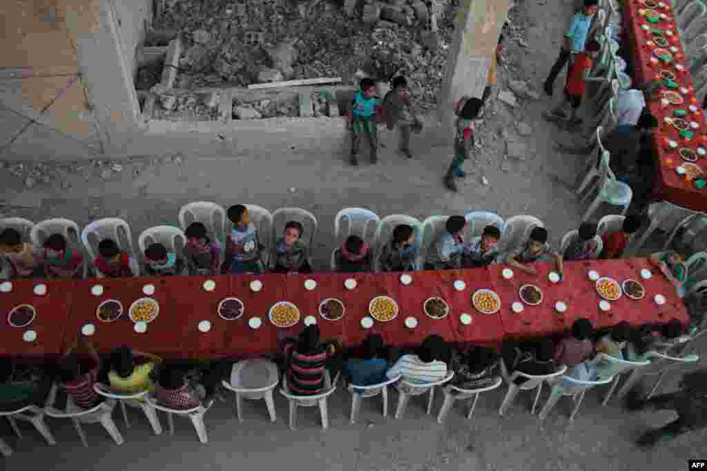 Syrian residents of the rebel-held town of Douma, on the outskirts of the capital, Damascus, break their fast with the iftar meal on a heavily damaged street during the Muslim holy month of Ramadan. (AFP/Hamza Al-Ajweh)