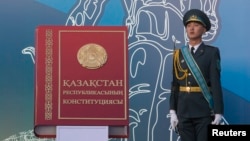 Военнослужащий стоит рядом с макетом Конституции.