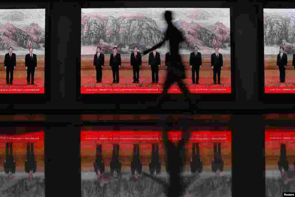 A pedestrian walks past electronic signs displaying pictures of China's Politburo Standing Committee members at a subway station in downtown Shanghai. (Reuters/Carlos Barria)
