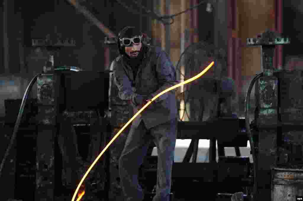 An Afghan worker holds a molten iron rod at a factory in Jalalabad. (epa/Ghulamullah Habibi)