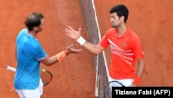 Rafael Nadal (stânga în această fotografie în care dă mâna cu Djokovici în 2019, la Roma) a spus că Djokovici știa de regulile competiției Australian Open din 2022 când a ales să nu se vaccineze. După decizia de luni, el i-a urat sârbului mult noroc.