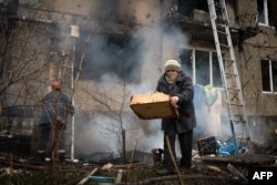 O femeie încearcă să-și salveze lucrurile după un bombardament în Donețk.