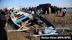 PAKISTAN -- Pilgrims wait beside a boat after it capsized while carrying pilgrims to the shrine of Saint Moy Pithi, in Gharo, near Thatta, December 8, 2017