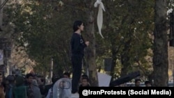 Протест девушки без платка, стоящей по улице Энгелаб в Тегеране, против исламского дресс-кода в Иране. Иллюстративное фото.