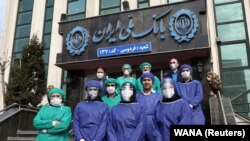 په ايران کې د ملي بېنک کارکوونکو د کورونا وایرس څخه بچ کېدو لپاره ځانګړې جامې اغوستې دي