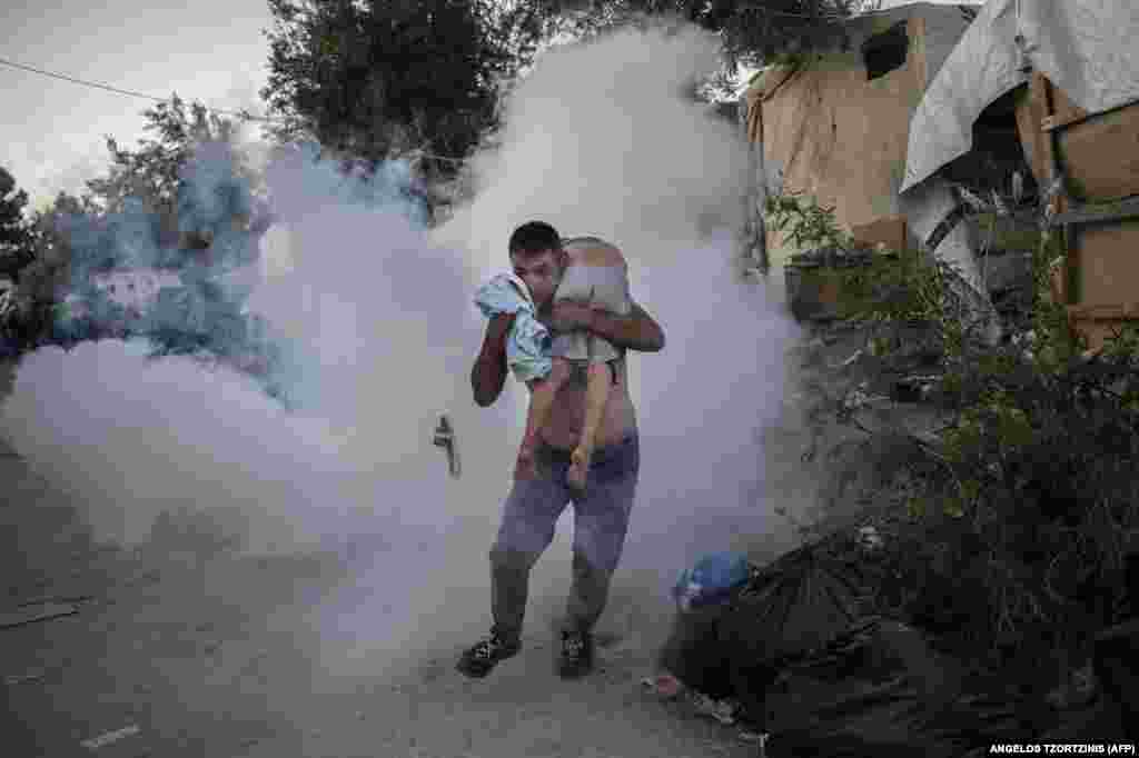 A man holds a boy during clashes with police outside the Moria refugee camp on the Greek island of Lesbos on September 29. (AFP/Angelos Tzortzinis)