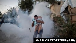 A man holds a boy during clashes with police outside the refugee camp of Moria on the Greek island of Lesbos on September 29.