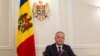 A file photo of Moldovan President Igor Dodon with the country's current tricolor flag in the background.