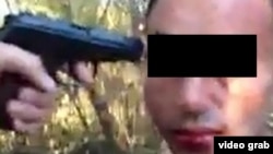 Скриншот размещенного в социальной сети видеоролика, где мужчина, которому угрожают пистолетом, подвергается изнасилованию.