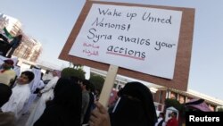 A protester in Bahrain holds a banner saying ''Wake up United Nations, Syria waits for your action'' as she protests outside the UN House in Manama on December 30.