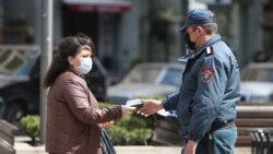 Armenia -- A police officer enforcing a coronavirus lockdown checks a woman's documents, Yerevan, March 25, 2020.