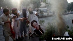 Supporters of Pakistani radical groups burn a poster of Pakistani Prime Minister Imran Khan in the southern city of Karachi on November 2.