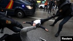 Police drag away demonstrators outside a banned polling station in Barcelona.